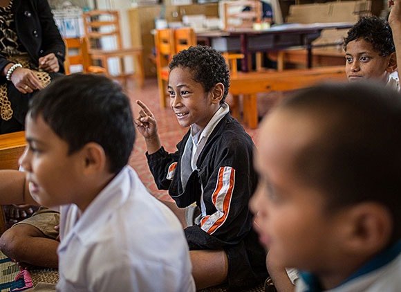 Kid Raising His Hand In A Classroom