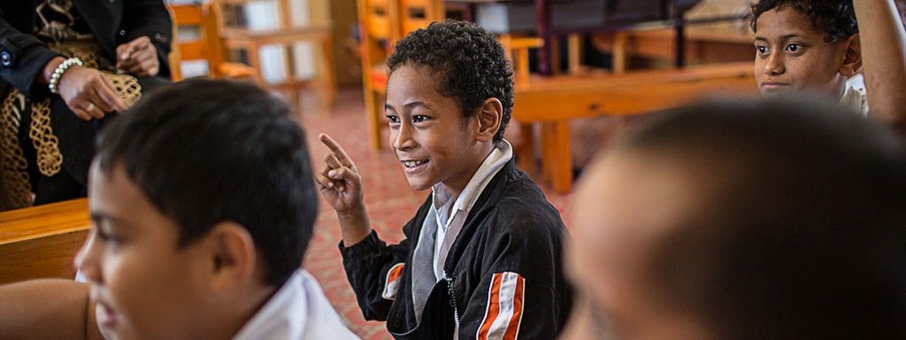 Kid Raising His Hand In A Classroom