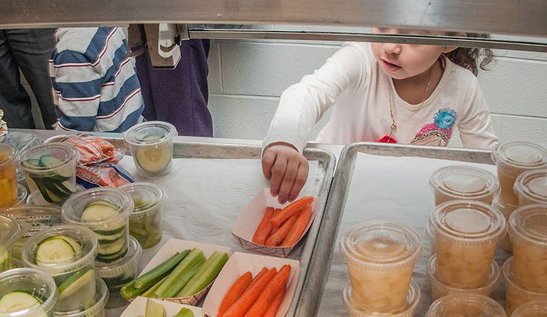 Kid Pick Up Carrots In A Cafeteria